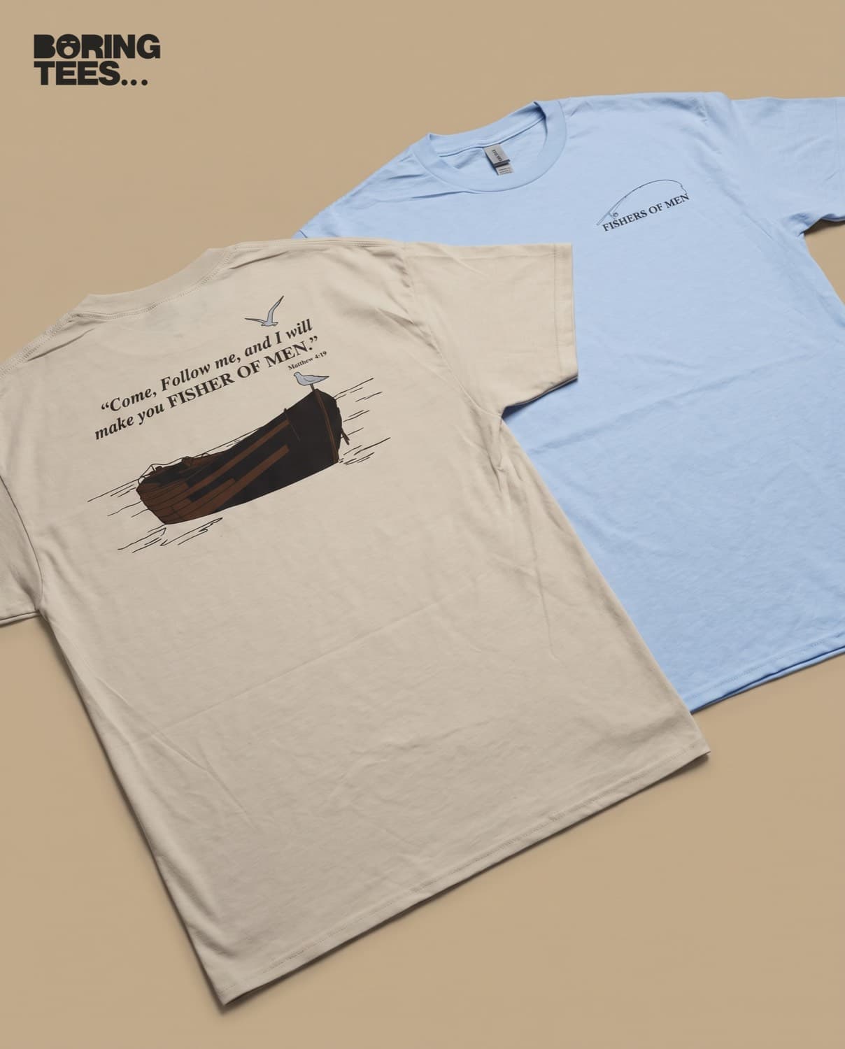 Stone and light blue tees laid together, one showing an illustrated boat back print and the other a small chest fishing rod mark