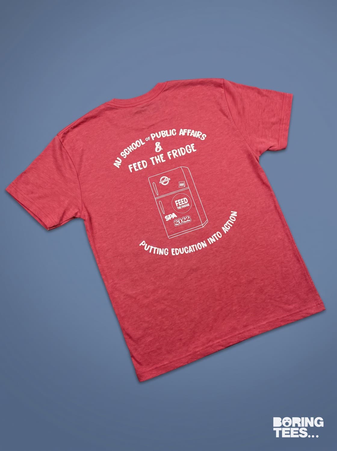 Heather red tee with a white back print showing a fridge illustration and arced text reading AU School of Public Affairs and Feed the Fridge