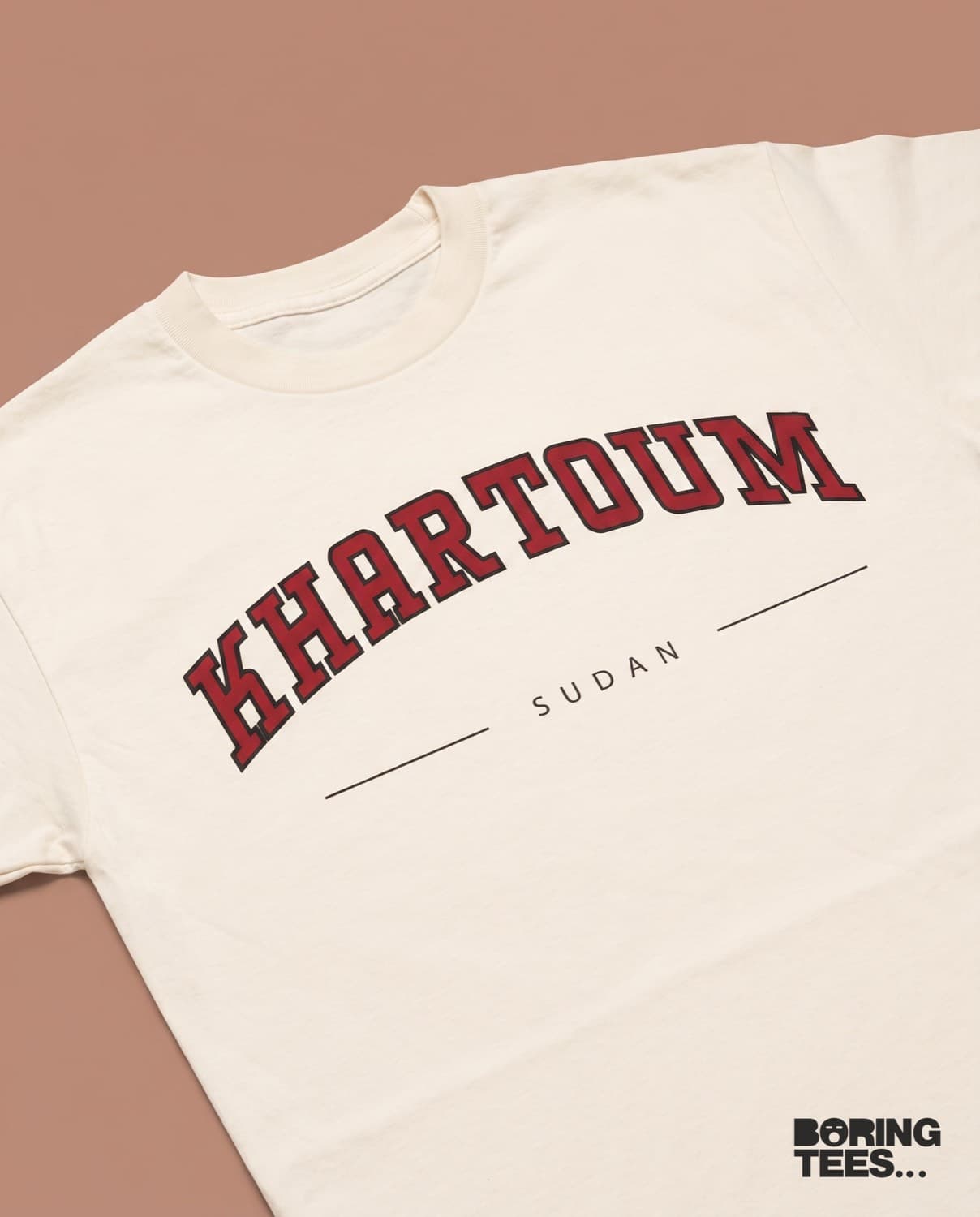 Cream tee with KHARTOUM in red collegiate slab type outlined in black, with SUDAN beneath